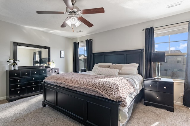 bedroom with light carpet, visible vents, a textured ceiling, and ceiling fan