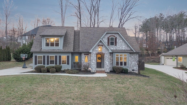 view of front facade with a front lawn, an outbuilding, driveway, and a shingled roof