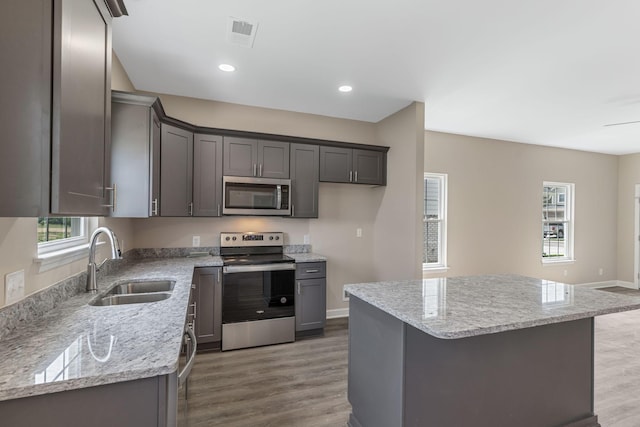 kitchen featuring wood finished floors, baseboards, visible vents, a sink, and stainless steel appliances