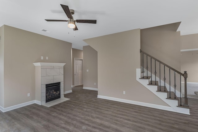 unfurnished living room featuring visible vents, baseboards, stairway, a fireplace, and wood finished floors