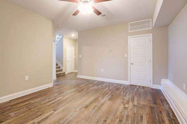 unfurnished room featuring visible vents, a ceiling fan, wood finished floors, stairway, and baseboards