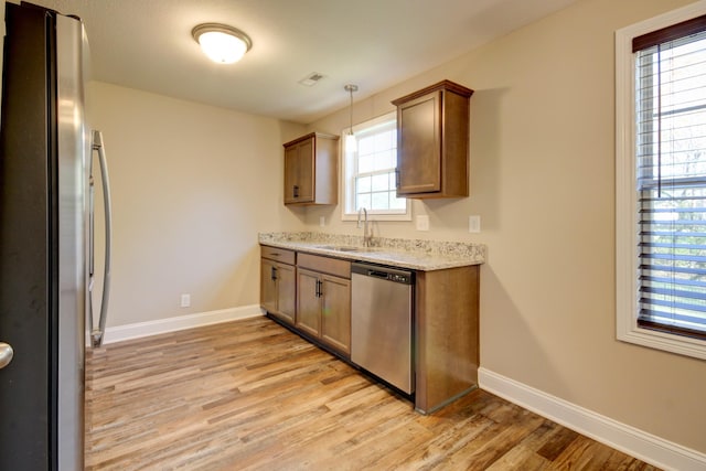 kitchen featuring baseboards, visible vents, light wood-style flooring, a sink, and stainless steel appliances