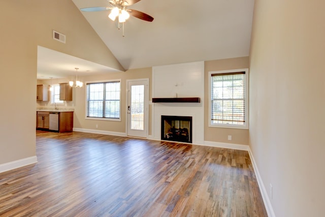 unfurnished living room with visible vents, plenty of natural light, wood finished floors, and a fireplace