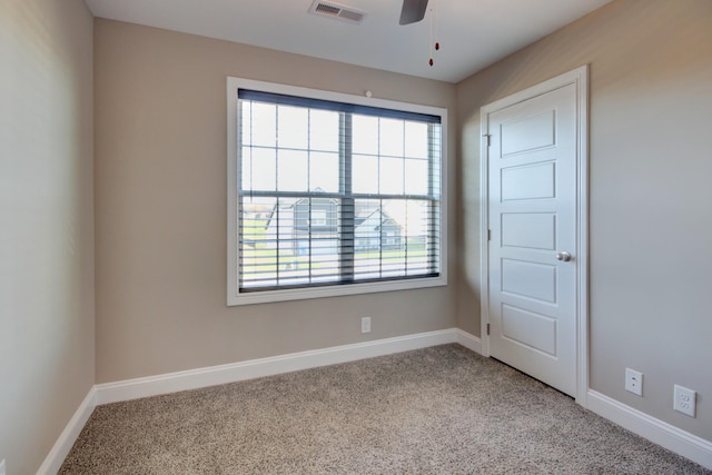 empty room featuring visible vents, a healthy amount of sunlight, carpet flooring, and baseboards