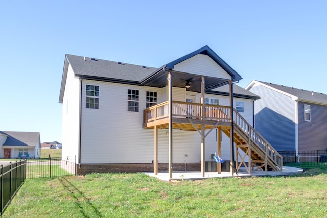 rear view of house with fence, stairway, a wooden deck, a lawn, and a patio area