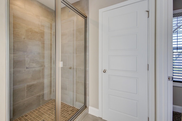 bathroom featuring baseboards and a shower stall