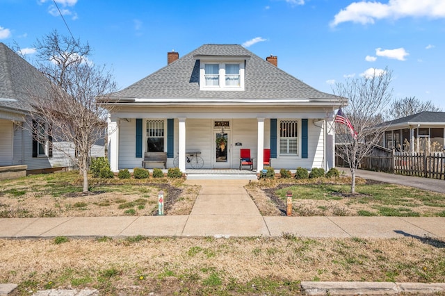 bungalow-style home featuring a porch, a chimney, and a shingled roof