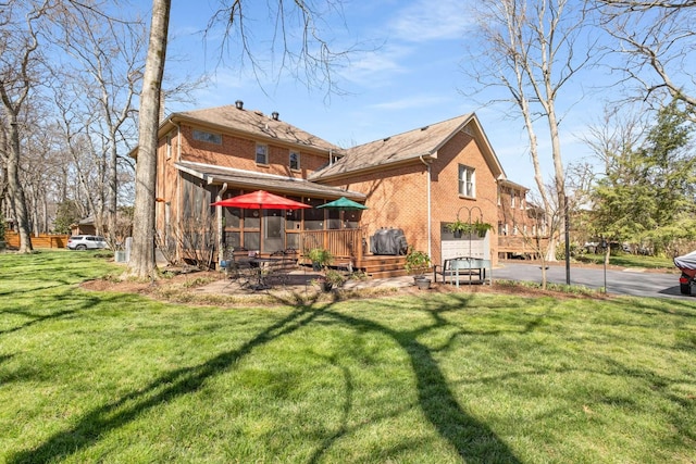 back of property with aphalt driveway, a garage, a lawn, and brick siding