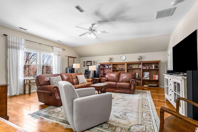 living area featuring visible vents, lofted ceiling, and light wood finished floors