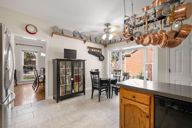 kitchen featuring brown cabinets, black dishwasher, stainless steel fridge with ice dispenser, baseboards, and ceiling fan