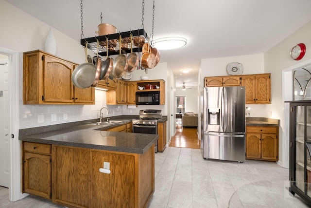 kitchen featuring brown cabinetry, appliances with stainless steel finishes, a peninsula, and a sink