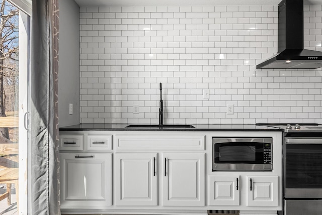 928 Red Bird Ln, Cumberland Furnace, TN 37051 - kitchen featuring dark countertops, decorative backsplash, appliances with stainless steel finishes, wall chimney exhaust hood, and a sink