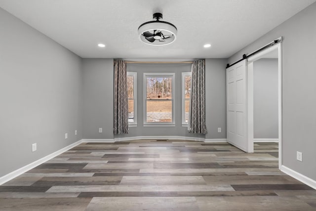 928 Red Bird Ln, Cumberland Furnace, TN 37051 - unfurnished bedroom with a barn door, baseboards, and wood finished floors