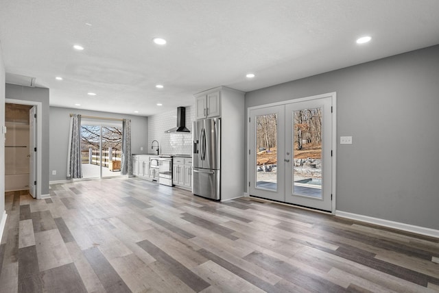 928 Red Bird Ln, Cumberland Furnace, TN 37051 - kitchen with backsplash, wall chimney range hood, light wood-type flooring, appliances with stainless steel finishes, and french doors