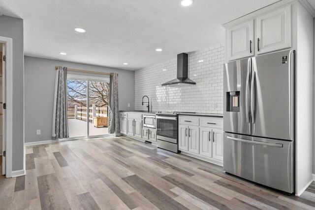 928 Red Bird Ln, Cumberland Furnace, TN 37051 - kitchen featuring a sink, decorative backsplash, light wood-style floors, appliances with stainless steel finishes, and wall chimney range hood