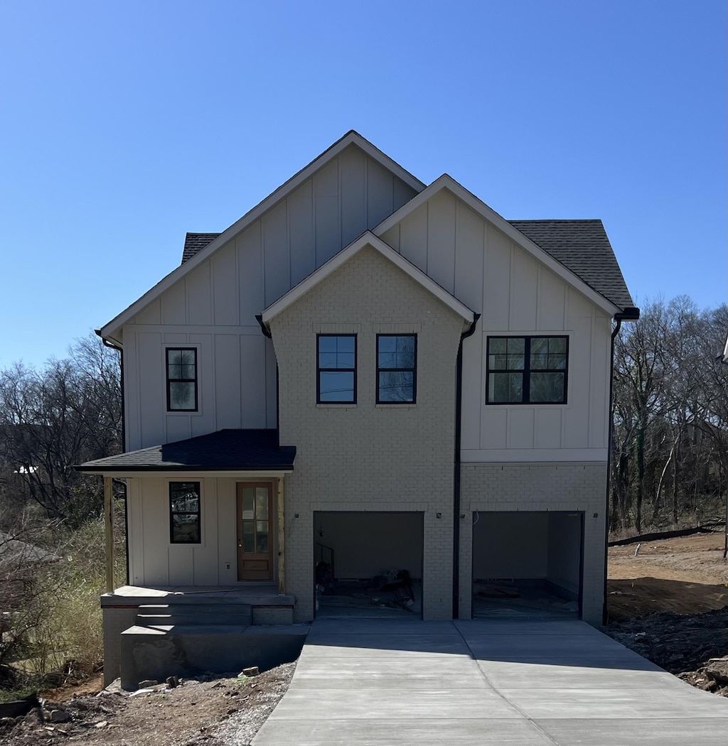 modern farmhouse with board and batten siding, concrete driveway, a shingled roof, a garage, and brick siding