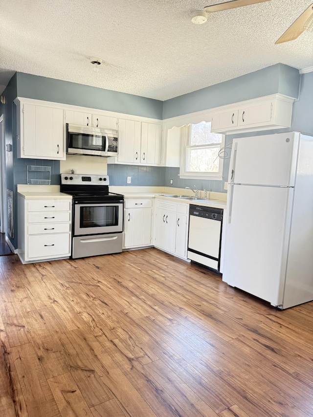 kitchen with a sink, appliances with stainless steel finishes, light wood-style flooring, and light countertops