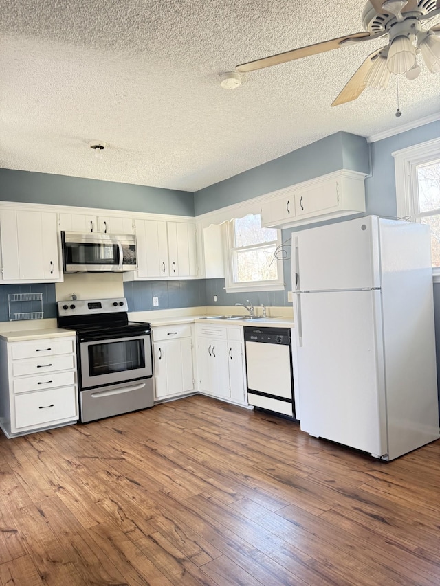 kitchen with dark wood finished floors, stainless steel appliances, decorative backsplash, light countertops, and white cabinetry