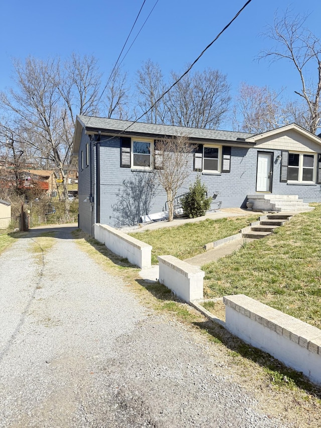 view of front of property with brick siding, driveway, and a front lawn