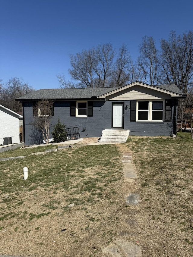 view of front facade featuring cooling unit, brick siding, and a front lawn