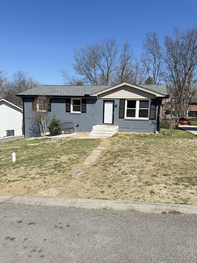 view of front of home with a front lawn, brick siding, and a shingled roof