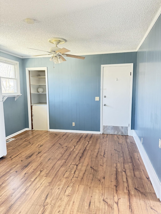 empty room featuring a textured ceiling, crown molding, and hardwood / wood-style flooring