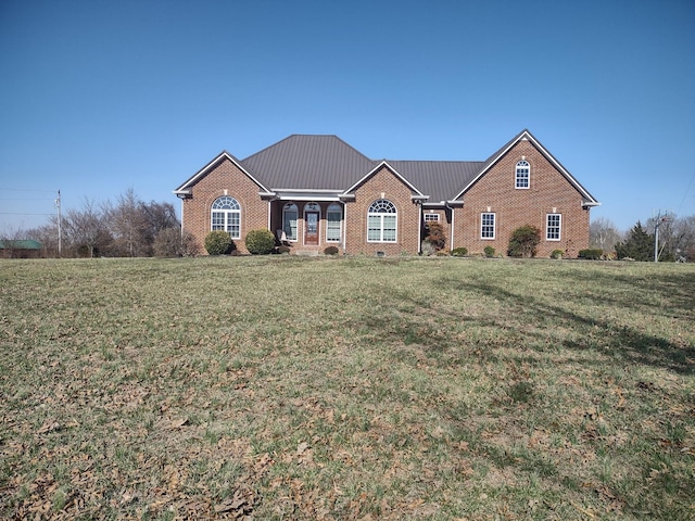 view of front of home featuring brick siding, crawl space, metal roof, and a front yard