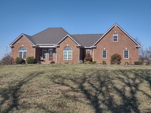 view of front facade featuring metal roof, brick siding, and a front yard