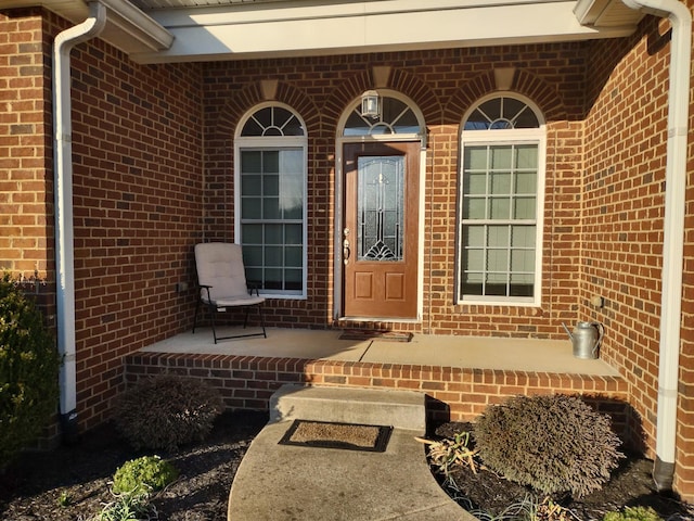 doorway to property with brick siding and a porch