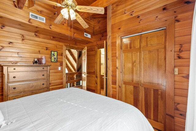 bedroom with a closet, wooden walls, and visible vents