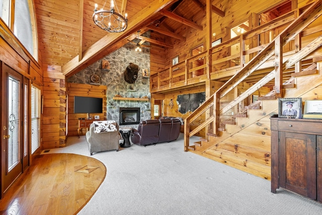 living room with beam ceiling, stairway, carpet floors, wooden walls, and wood ceiling