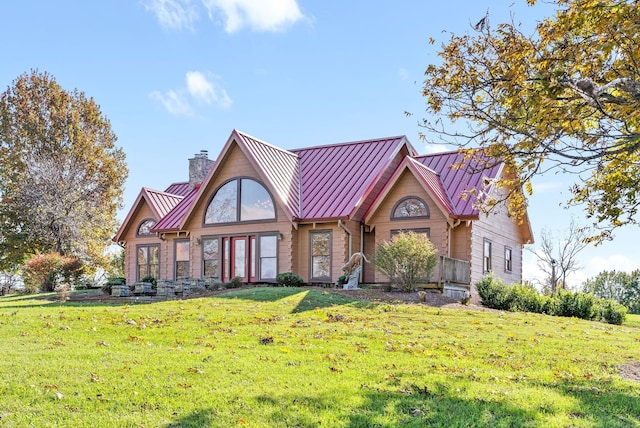 view of front of home featuring metal roof, a chimney, a front lawn, and a standing seam roof