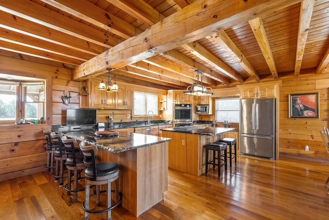 kitchen featuring plenty of natural light, light wood-type flooring, wood walls, and stainless steel appliances