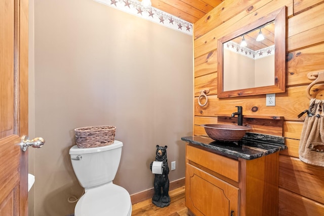 bathroom with toilet, vanity, baseboards, and wood finished floors