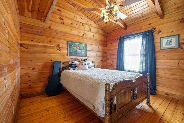 bedroom featuring a ceiling fan, wooden walls, light wood finished floors, wood ceiling, and vaulted ceiling with beams