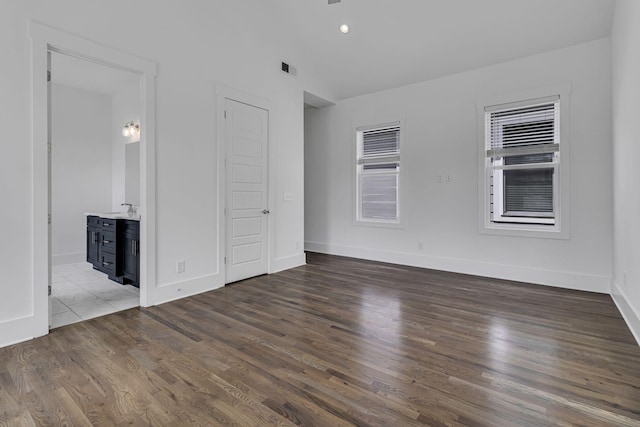 unfurnished bedroom featuring baseboards, recessed lighting, wood finished floors, ensuite bath, and a sink