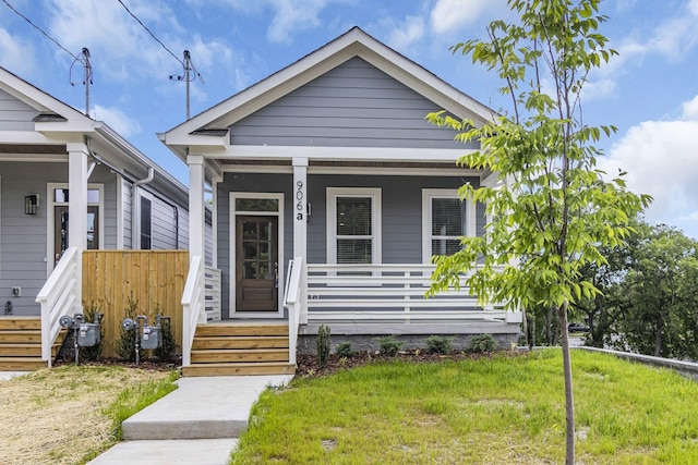 shotgun-style home with a front yard and covered porch