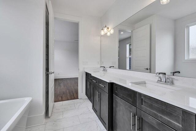 bathroom with double vanity, marble finish floor, baseboards, and a sink