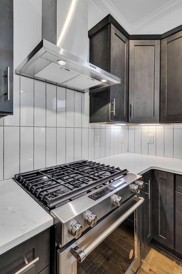 kitchen with tasteful backsplash, stainless steel range with gas stovetop, ornamental molding, and wall chimney range hood