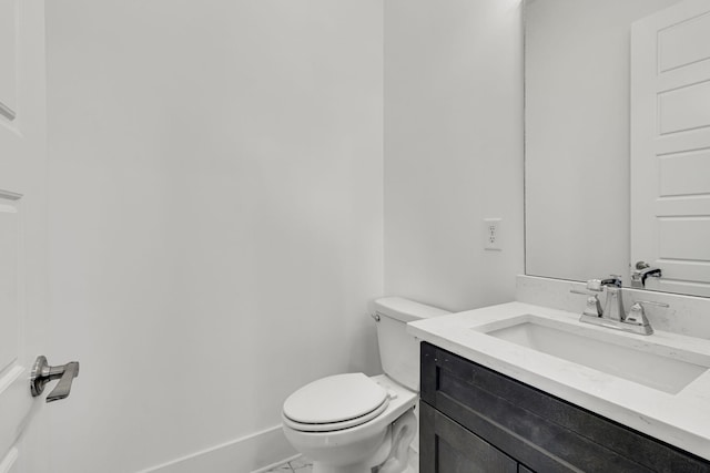 half bathroom featuring baseboards, toilet, and vanity