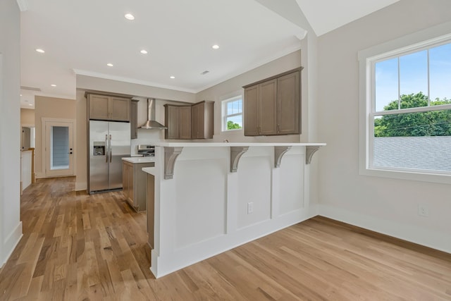 904 32nd Ave N Unit A, Nashville, TN 37209 - kitchen featuring stainless steel fridge, wall chimney range hood, a breakfast bar area, crown molding, and light countertops
