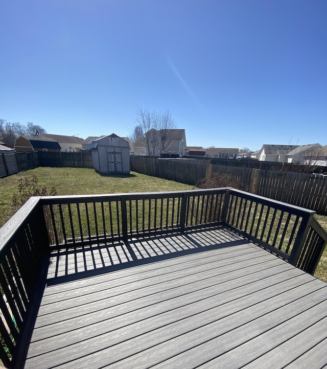 wooden deck featuring a fenced backyard, an outdoor structure, a storage shed, a lawn, and a residential view