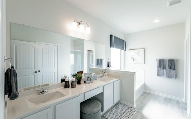 bathroom with visible vents, double vanity, a sink, a shower stall, and a garden tub