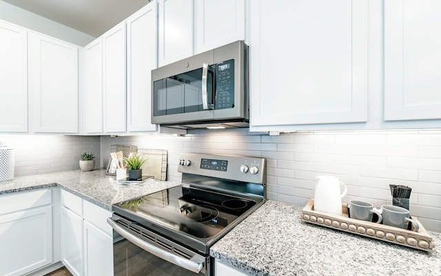 kitchen with tasteful backsplash, appliances with stainless steel finishes, and white cabinetry