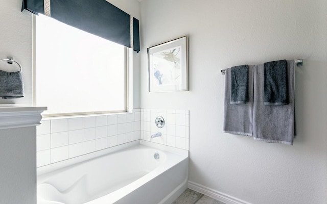 bathroom featuring baseboards and a bath