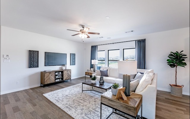 living room featuring visible vents, baseboards, a ceiling fan, and wood finished floors