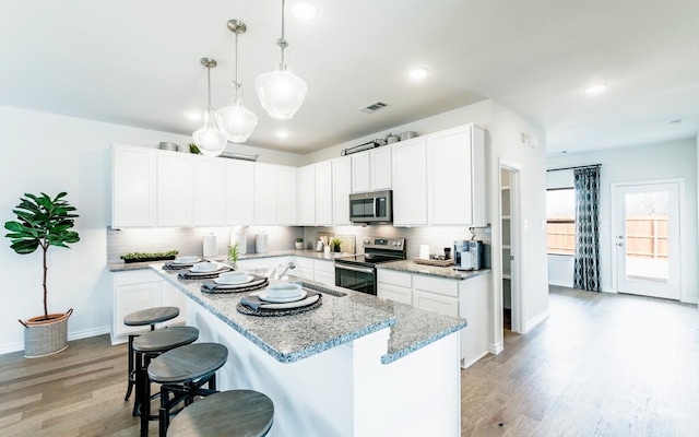 kitchen featuring light wood-type flooring, a kitchen bar, visible vents, a kitchen island, and stainless steel appliances