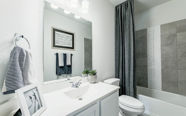 bathroom featuring toilet, shower / tub combo with curtain, vanity, and a textured wall