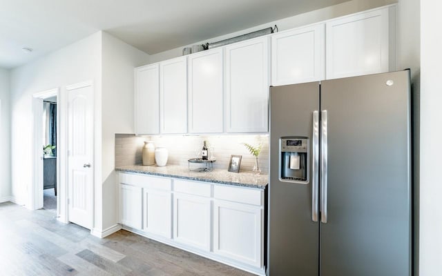 kitchen featuring backsplash, light stone countertops, white cabinetry, and stainless steel fridge with ice dispenser