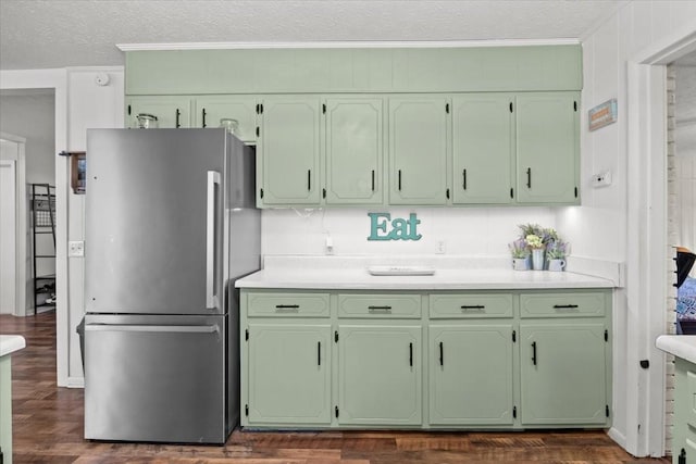 kitchen with green cabinets, light countertops, freestanding refrigerator, and a textured ceiling